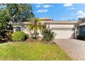 Tan house with palm trees, lush landscaping, and a brick driveway at 108 Corte Del Rosa, Venice, FL 34285
