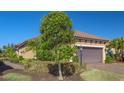 Front yard of the home, featuring a tree, shrubs, and a paved walkway leading to the entrance at 12667 Sorrento Way, Bradenton, FL 34211