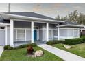 Gray house with blue door, columned porch, and landscaped yard at 566 Oak Bay Dr, Osprey, FL 34229