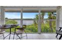 Screened porch with water views, wicker chairs and a small dining table at 6029 E Peppertree Way # 116, Sarasota, FL 34242