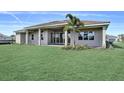 Expansive backyard of this home, with lush green grass, tropical trees, and a covered patio for entertaining at 8007 Nevis Run, Bradenton, FL 34202