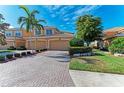 Paver driveway, manicured lawn, and palm trees frame the front of this lovely home at 318 Winding Brook Ln # 104, Bradenton, FL 34212
