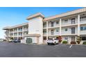 Exterior of condo building showing balconies, parking lot, and landscaping at 3330 Gulf Of Mexico Dr # 205D, Longboat Key, FL 34228