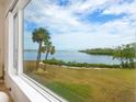 Scenic water view from a large window with blue sky and palm trees at 3330 Gulf Of Mexico Dr # 205D, Longboat Key, FL 34228