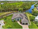 Stunning aerial view of a waterfront house with lush landscaping and a private boat dock on the serene water at 609 Colonial Bay Dr, Nokomis, FL 34275