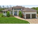 Charming home with a well-manicured lawn, brick driveway, and a welcoming entrance with a double garage at 609 Colonial Bay Dr, Nokomis, FL 34275