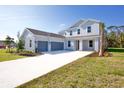 The two-story home has a light-gray exterior, 3 car garage, and a long driveway with green grass and landscaping at 9153 Radiant Cir, Sarasota, FL 34241