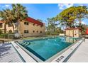 Well-maintained community pool with mature shade trees and adjacent cabana with a red roof and white trim at 207 Rubens Dr # D, Nokomis, FL 34275