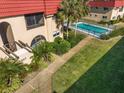 Condo with red tile roof, lush tropical landscaping and community pool with black fencing at 207 Rubens Dr # D, Nokomis, FL 34275