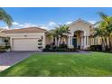 Beautiful one-story home with a three car garage, blue front door and well manicured landscaping at 805 Riviera Dunes Way, Palmetto, FL 34221