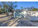 A single car garage with a unique blue-green door surrounded by bright white walls and lush foliage at 104 23Rd St, Bradenton Beach, FL 34217