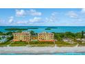 Oceanfront condo building with white sandy beach and tropical landscaping at 4125 Gulf Of Mexico Dr # S201, Longboat Key, FL 34228