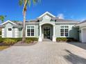 Elegant home exterior featuring a light-green facade and a paver driveway at 8325 Lindrick Ln, Bradenton, FL 34202