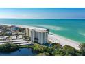 Gorgeous aerial view of a high-rise condo building on a white sandy beach with clear, turquoise water at 19 Whispering Sands Dr # 301, Sarasota, FL 34242