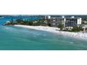 Expansive view of a white sandy beach, turquoise water, and condo buildings in the distance at 19 Whispering Sands Dr # 301, Sarasota, FL 34242