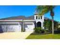 A home with a three-car garage, landscaped front yard and a stucco exterior is the main focal point of this photo at 4742 Balboa Park Loop, Bradenton, FL 34211