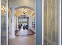 Elegant foyer with tile flooring, white columns, arched doorways, and a chandelier, offers a glimpse into the well-lit living area at 7115 Callander Cv, Lakewood Ranch, FL 34202