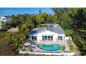 White house with a kidney-shaped pool, surrounded by lush tropical landscaping at 6061 Gulf Of Mexico Dr, Longboat Key, FL 34228