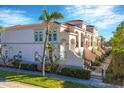 Multi-story townhome featuring a tile roof, arched windows, and well-manicured landscaping and palm trees at 461 Nokomis S Ave, Venice, FL 34285
