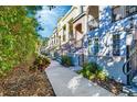 Exterior side view of townhomes with arched entryways, wrought iron railings, and landscaped sidewalk at 461 Nokomis S Ave, Venice, FL 34285