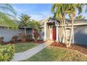 Inviting single-story home featuring lush landscaping and a vibrant red front door at 4877 Post Pointe Dr, Sarasota, FL 34233