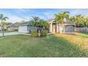 Beautiful single-story home featuring a well-manicured lawn and tropical landscaping at 4877 Post Pointe Dr, Sarasota, FL 34233