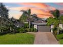 Single-Gathering home with gray garage door, landscaping, and palm trees at 942 Preservation St, Bradenton, FL 34208