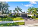 Beautiful home featuring a well-manicured lawn, palm trees, and a brick driveway with blue skies at 942 Preservation St, Bradenton, FL 34208