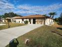 Single-story house with a driveway, landscaping, and two palm trees at 25484 Terrain Ln, Punta Gorda, FL 33983