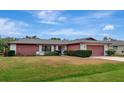 Red and white ranch home with a large lawn and brick paver driveway at 4423 Meadow Creek Cir, Sarasota, FL 34233