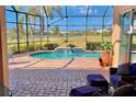 Enclosed pool area featuring a brick-paved deck, lounge furniture, and a serene view of the adjacent lake at 4423 Via Del Villetti Dr, Venice, FL 34293