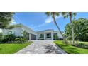 Beautiful single-story home with lush landscaping, a gray driveway, and a modern architectural style at 4815 Featherbed Ln, Siesta Key, FL 34242