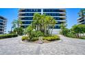 Elegant condominium exterior showcasing lush tropical landscaping at the entrance at 575 Sanctuary Dr # A303, Longboat Key, FL 34228