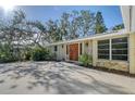Front entrance with large wooden door, stone accents, mature trees, and expansive concrete driveway at 640 Venice Ln, Sarasota, FL 34242
