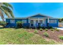 Charming blue home with a manicured lawn and landscaping, evoking a welcoming and vibrant curb appeal at 2820 Wood St, Sarasota, FL 34237