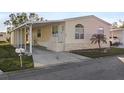 Front view of a manufactured home with carport, steps, and palm tree at 3386 Oakwood N Blvd, Sarasota, FL 34237