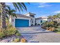 Beautiful home featuring a paver driveway, lush landscaping, and a striking blue garage door at 4779 Pastel Ct, Sarasota, FL 34240
