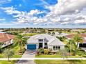 Bright exterior showcasing lake views, tile roof, a lush landscape, and a blue garage door at 4779 Pastel Ct, Sarasota, FL 34240