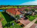 One-story house with a red tile roof, and brick paver driveway in a golf course community at 24160 Gallberry Dr, Venice, FL 34293