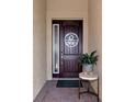 Front entry with a dark wood door, a circular monogram, and a small table with a plant at 24160 Gallberry Dr, Venice, FL 34293