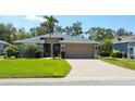Inviting single-story home features a well-manicured lawn, mature landscaping, and a brick-paved driveway leading to a two-car garage at 5115 44Th St W, Bradenton, FL 34210