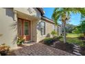 Elegant front door with glass panels, complemented by a brick walkway and lush landscaping at 5846 Cavano Dr, Sarasota, FL 34231