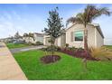 Beige house with gray driveway and lush green landscaping at 8780 Coco Bay Blvd, Englewood, FL 34224