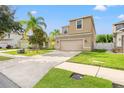 Two-story house with beige exterior, two-car garage, and manicured lawn at 1964 Hawks View Dr, Ruskin, FL 33570