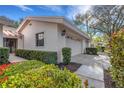 Well-maintained home exterior with lush landscaping and a view of the two-car garage at 5436 Hampstead Heath # 25, Sarasota, FL 34235