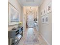 Inviting hallway with elegant decor, featuring a patterned rug and decorative artwork, leading to a glass-paneled front door at 10379 Medjool Dr, Venice, FL 34293