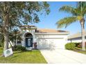 Charming single-story home featuring a well-manicured lawn, blue door, tile roof, and a two-car garage at 236 Golden Harbour Trl, Bradenton, FL 34212