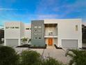 Stylish two-story home with a modern design, featuring a bright orange door, balcony, and landscaped yard at 3939 Higel Ave, Sarasota, FL 34242