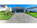 Inviting single-story home with lush front lawn and elegant stone-paved driveway leading to a dark colored attached garage at 4514 Big Woods Way, Parrish, FL 34219
