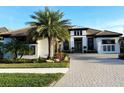 Beautiful two-story home with lush landscaping, palm trees, and a brick driveway at 5305 Brookgrove Dr, Sarasota, FL 34238